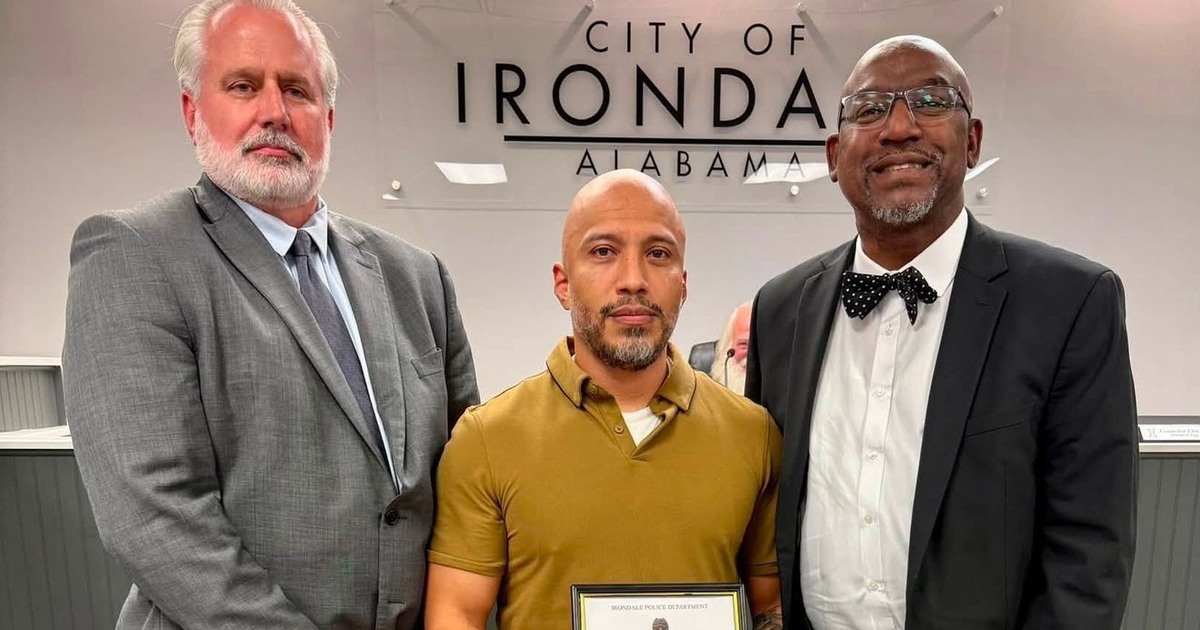 Irondale Police Corporal Pedro Urresta holding his commendation between city officials at an Irondale City Council recognition ceremony.