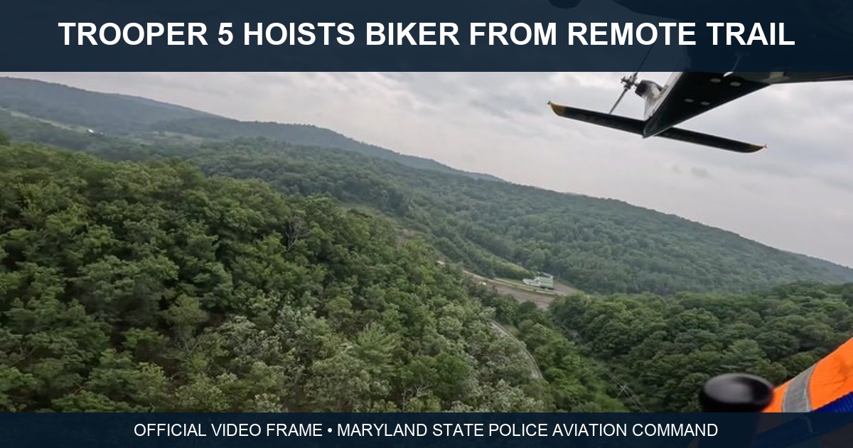 Official Maryland State Police Aviation Command video frame showing the forested Rocky Gap area and part of Trooper 5 during a mountain biker hoist rescue.