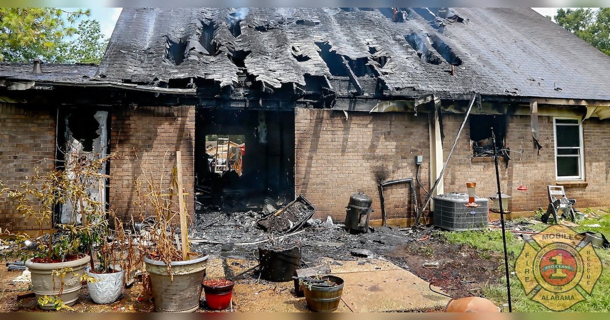 Mobile Fire-Rescue Department photograph showing heavy fire damage to the rear of a brick home after an off-duty officer and bystanders helped a resident who uses a wheelchair escape.