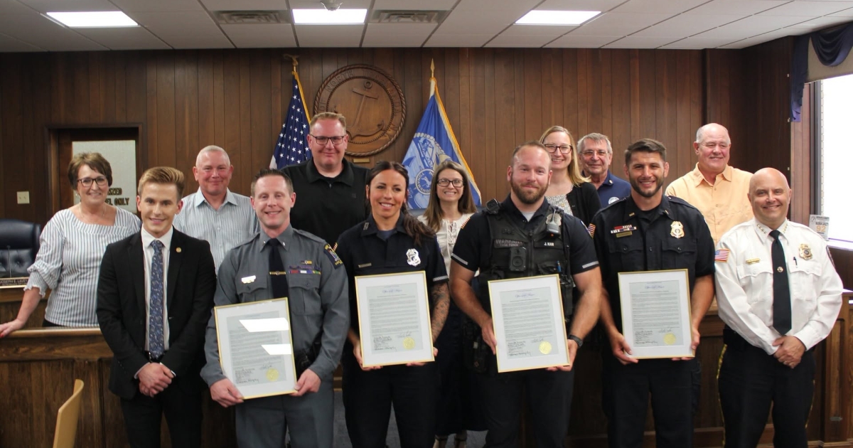 North Tonawanda recognition photo showing four uniformed officers holding framed commendations with city officials and guests behind them.