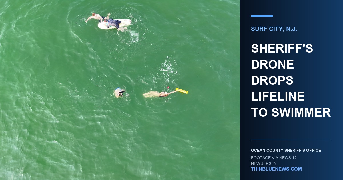 Ocean County Sheriff's Office drone-camera view of three swimmers in the ocean, including one holding a yellow flotation device dropped during the Surf City rip-current rescue.