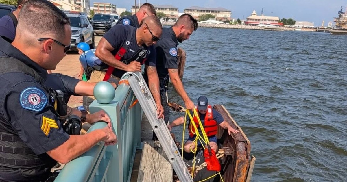 Pensacola police officers and firefighters use a ladder, ropes and flotation equipment during a real water rescue beside a seawall near Blue Wahoos Stadium.