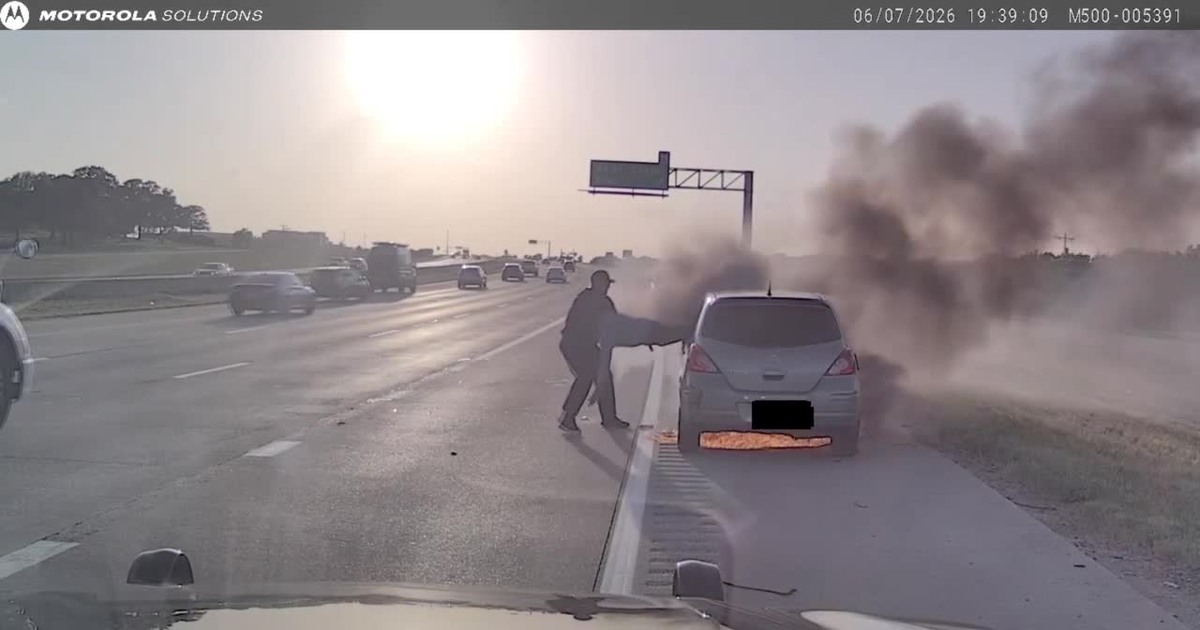 Southlake Police dash-camera frame showing Corporal Joshua Swisher beside a smoking vehicle on State Highway 114 during the June 7, 2026 rescue.