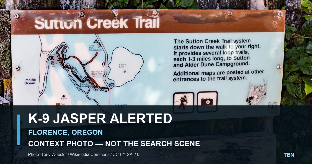 A licensed contextual photo of a trail sign near Florence, Oregon, with the words K9 Jasper Alerted and a label that it is not the search scene.
